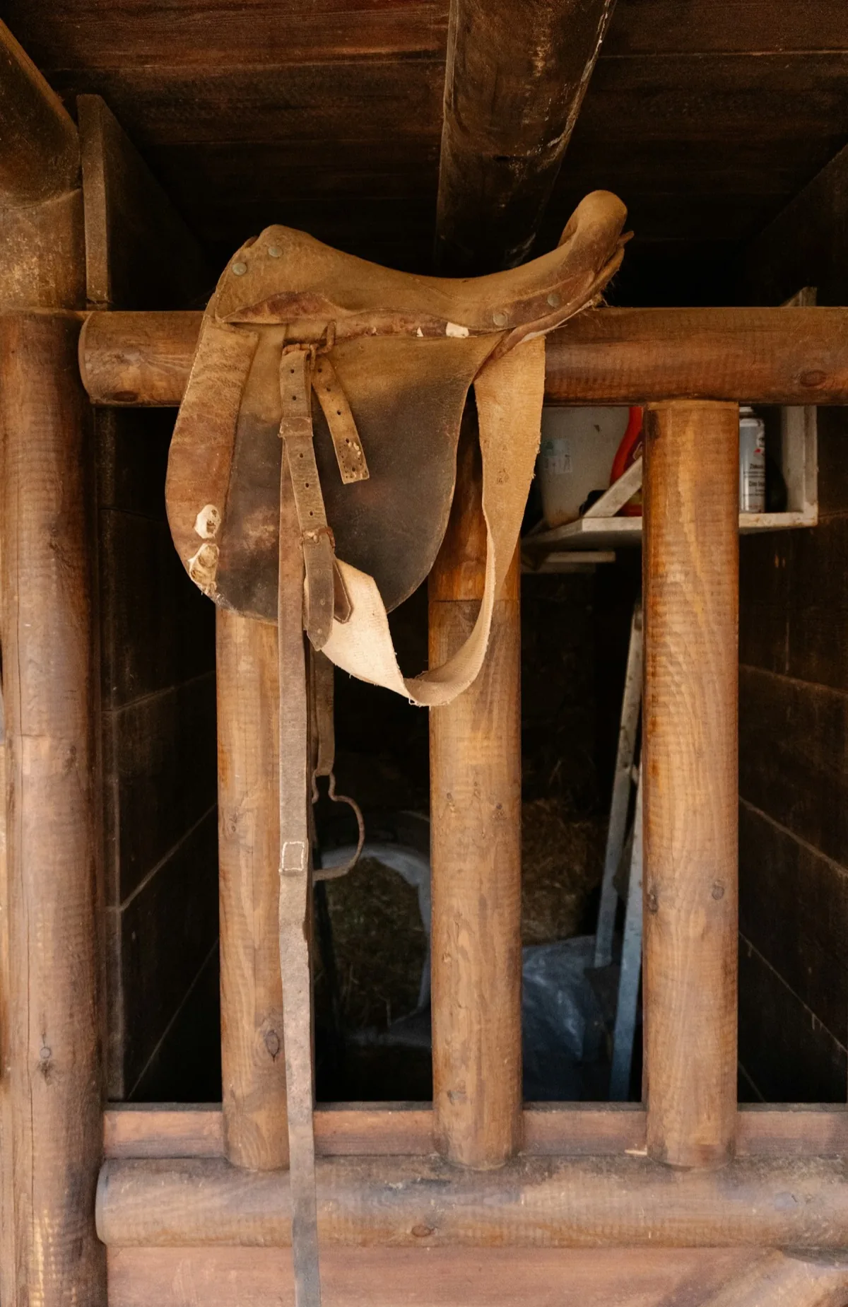 A tooled leather Western saddle resting on a wooden rack