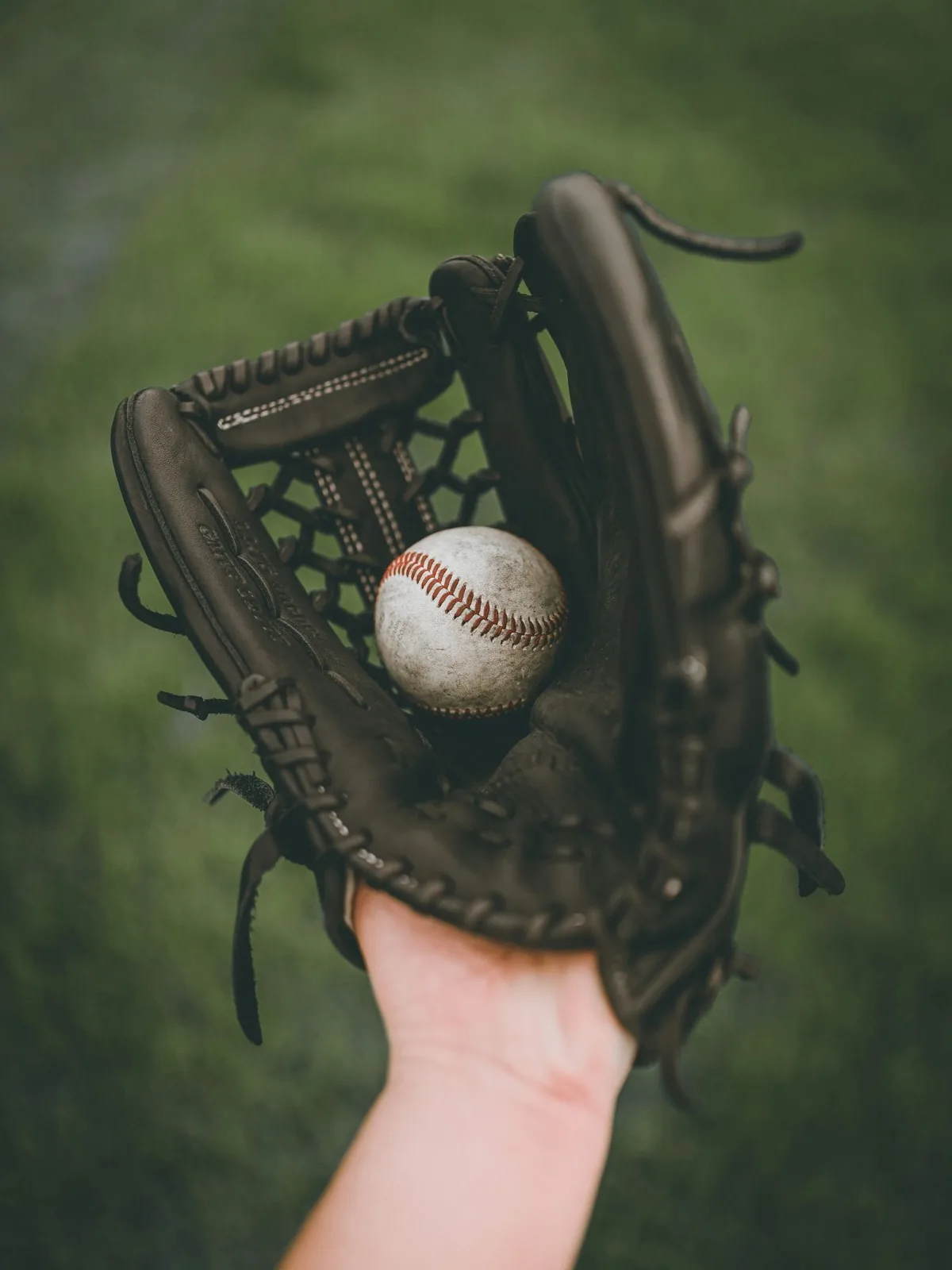 A worn baseball resting in a black leather glove